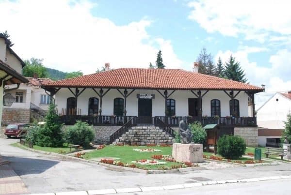 Zgrada sa crvenim krovom i spomenikom ispred ulaza