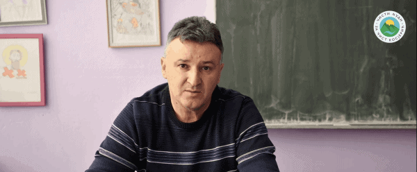 Мушкарац седи у учионици испред школске табле