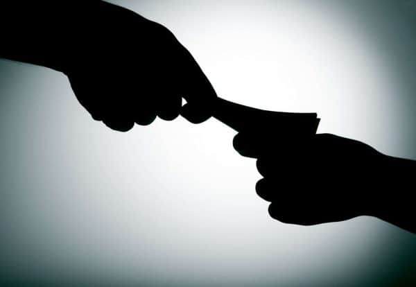 Силуете две руке размењују новац на сивој позадини