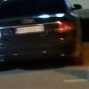 Задњи део црног аутомобила са регистарском таблицом ноћу