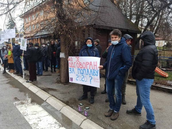 Група људи на протесту држи транспарент „Ко је одговоран за поплаву