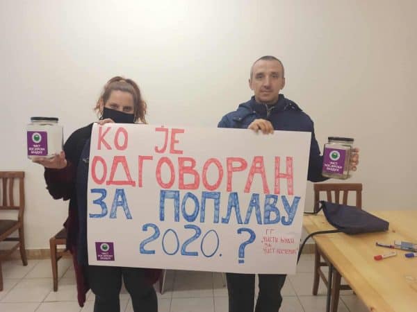 Двоје људи држи транспарент „Ко је одговоран за поплаву 2020?“